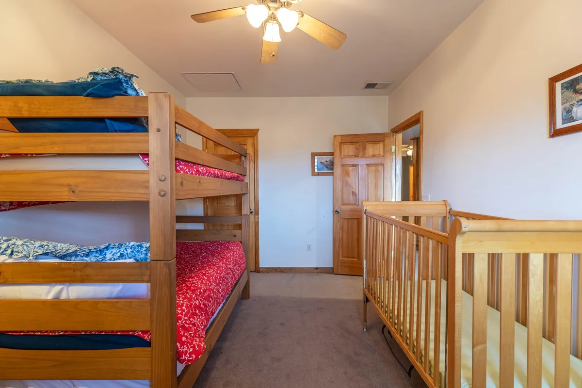 Inside the cabin, a cheerful room features sturdy wooden bunk beds and a crib, with plenty of space for children to sleep or play. The décor is simple and warm, making it a welcoming haven for the youngest family members.