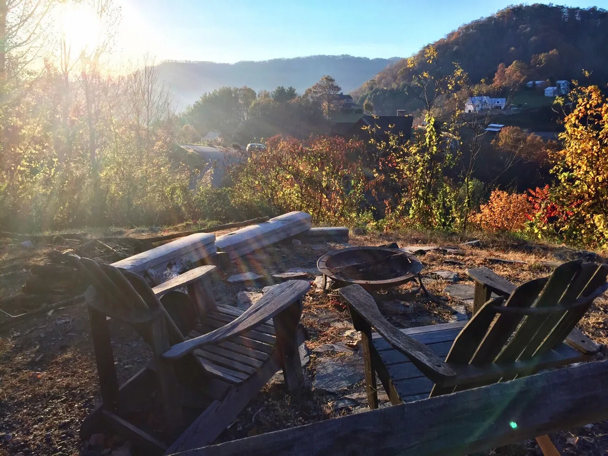 The image features wooden chairs arranged around a fire pit with a stunning natural landscape in the background. The setting is perfect for evening gatherings, storytelling, and stargazing, reinforcing the idea of group relaxation after daytime adventures.