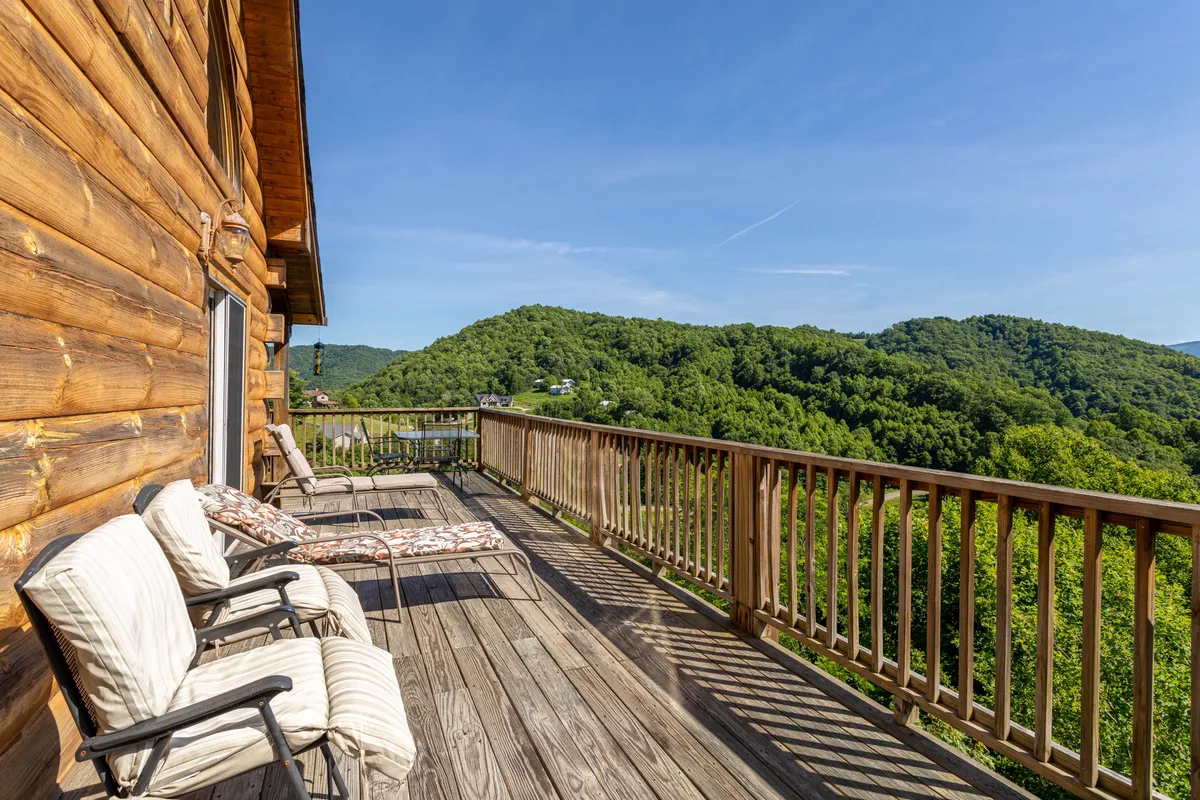 A peaceful wooden deck overlooks a stunning mountain vista, with lounge chairs set up for relaxation. The deck space is inviting for both people and pets, ideal for unwinding after a day of exploration.